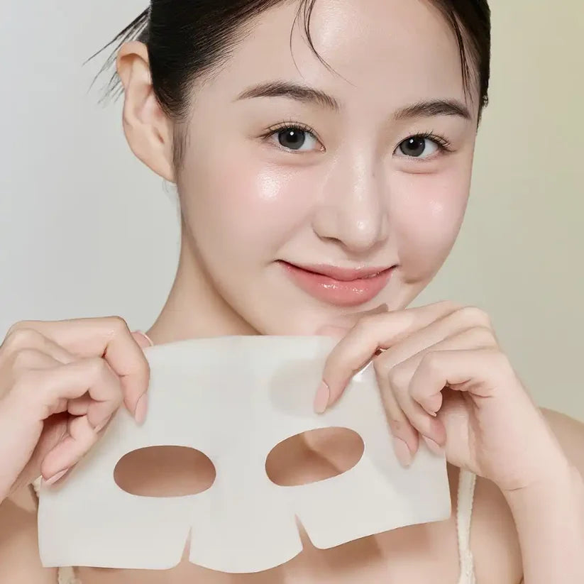 Gros plan d'une femme à la peau éclatante et hydratée montrant un masque en hydrogel transparent après utilisation.
