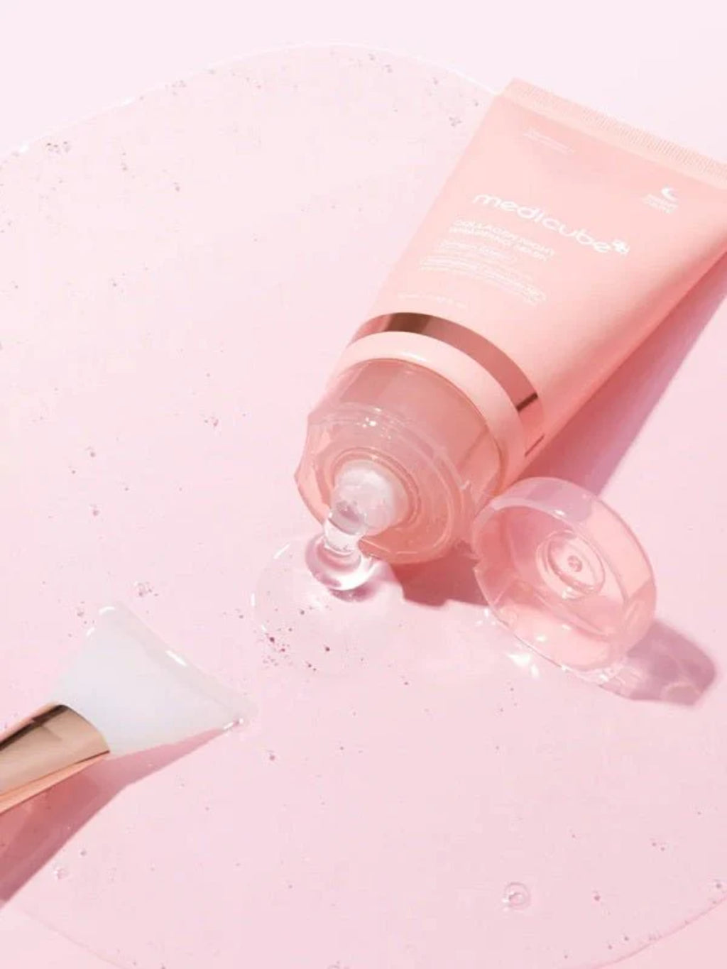 Flacon du masque de nuit Collagen Night Wrapping Peel Off Mask de Medicube sur une table blanche avec le liquide qui sort du tube