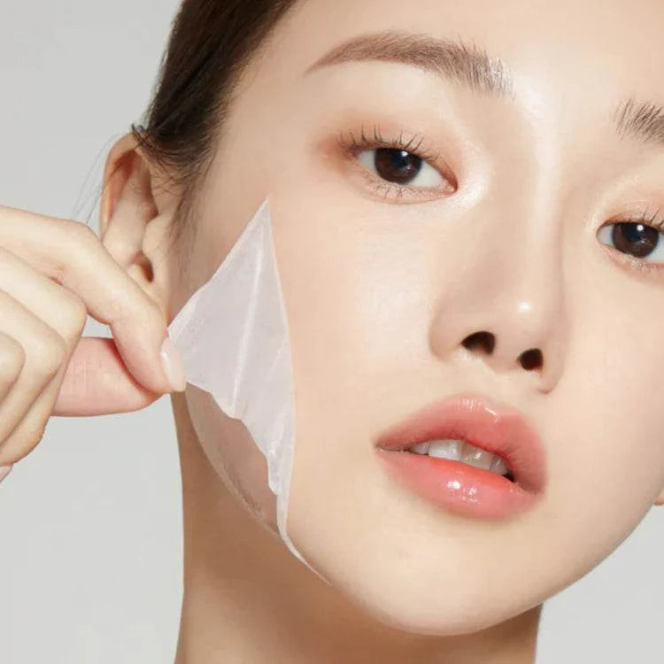 Application du masque en film transparent Medicube au collagène sur le visage pour un effet peeling de nuit